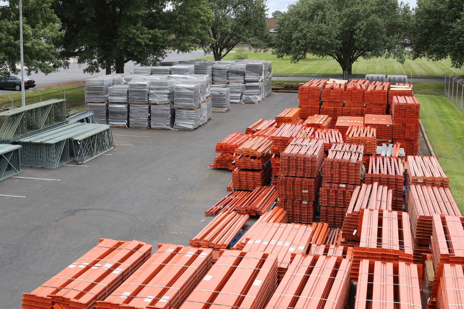 The Stein lot from above, with banded orange beams, pallets of wire decks, and green uprights laid out across the pavement