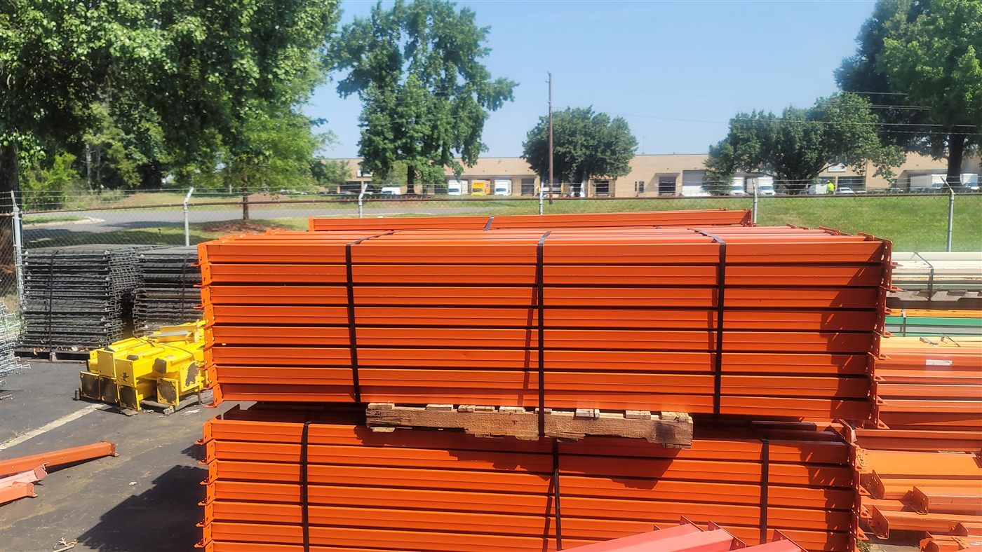 Banded stacks of orange used rack beams on the lot behind the Stein building